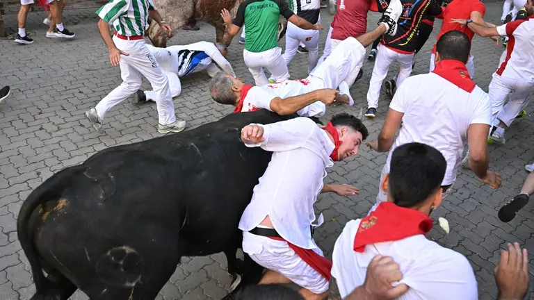 Un mozo caído, durante del séptimo encierro de los sanfermines con toros de la ganadería de Victoriano del Río y dos minutos y 18 segundos de duración, este jueves en Pamplona. EFE/Daniel Fernandez