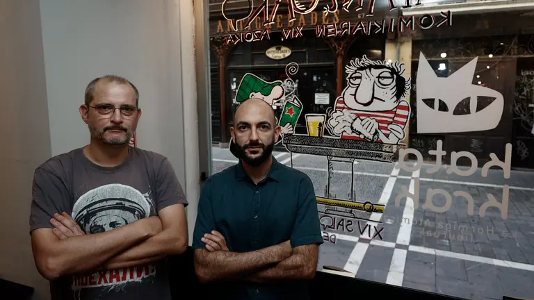 El artista Joseba Beramendi (i) conocido como "Exprai" y el director del Salón del Cómic de Navarra, Javier Pérez, posan junto al dibujo realizado por Joseba en un escaparate de un comercio en el Casco Viejo de Pamplona. EFE/ JESÚS DIGES