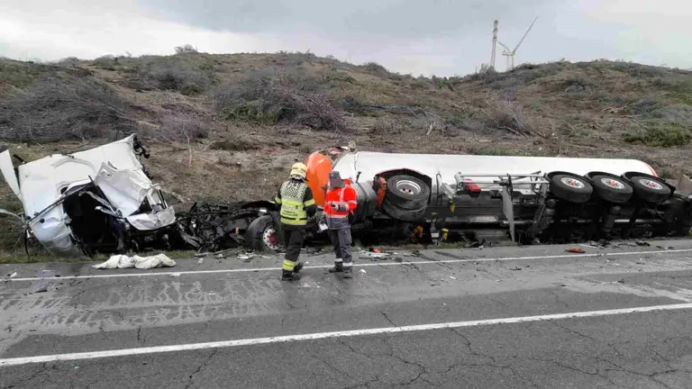 Un agente de la Policía Foral y un bombero ante uno de los camiones siniestrados en Los Abetos. POLICÍA FORAL