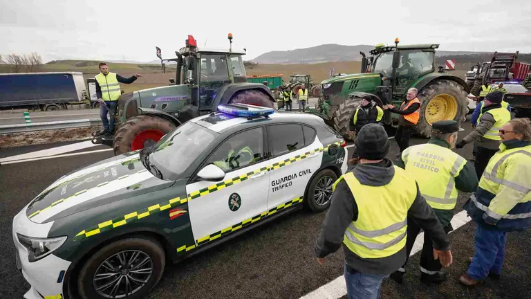 Agricultores en los accesos a Pamplona por el nudo de Cizur donde han apartado un coche patrulla de la Guardia Civil para poder pasar. EFE