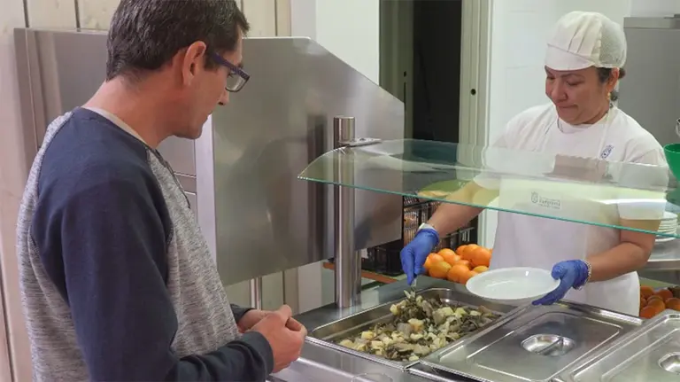 Una trabajadora atiende a un usuario del comedor On Egin de Pamplona. AYUNTAMIENTO DE PAMPLONA