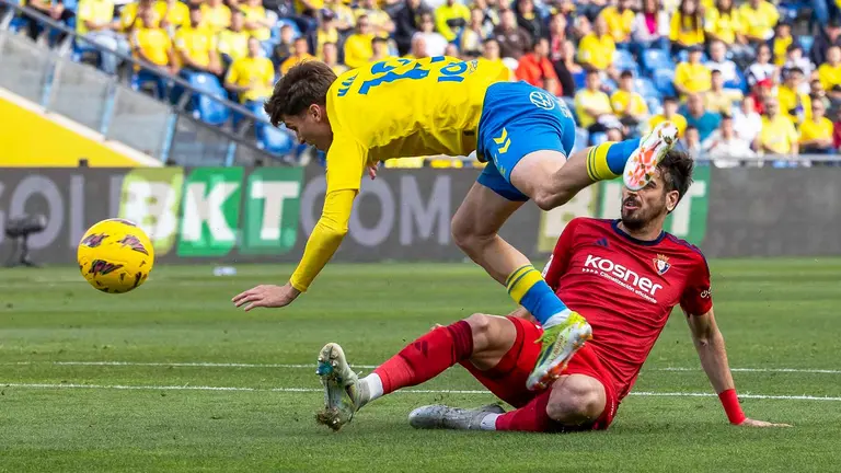 El delantero de Las Palmas Marc Cardona (i) cae ante Alejandro Catena, de Osasuna, durante el partido de Liga que UD Las Palmas y CA Osasuna disputan este domingo en el estadio de Gran Canaria. EFE/Quique Curbelo
