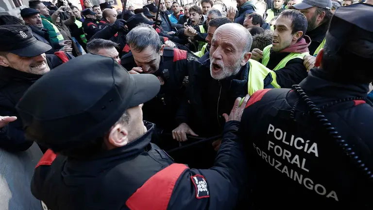 GRAFCAV9768. PAMPLONA, 07/03/2024.- Un grupo de agricultores ha tratado de acceder al interior del Parlamento de Navarra, lo que les ha sido impedido por la Policía Foral, en el momento en el que intervenía el portavoz socialista después de que se supiera que la Cámara no había admitido a trámite una enmienda de UPN que recogía sus demandas.EFE/ Jesus Diges