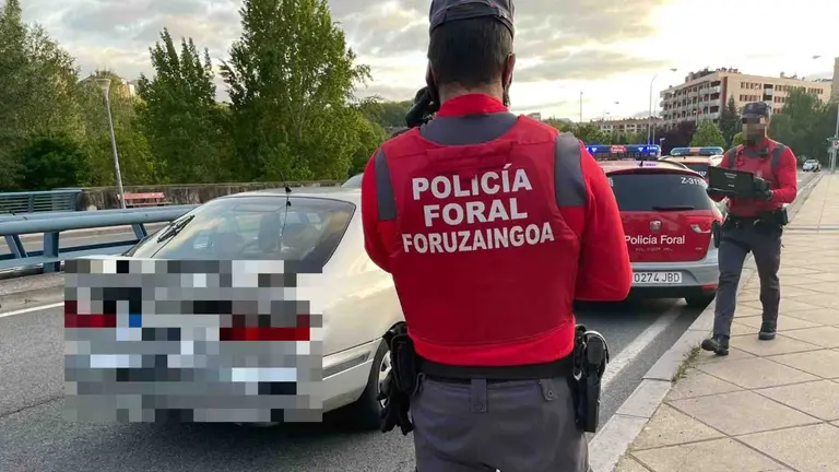 Los agentes de la Policía Foral junto al vehículo en el que viajaba el conductor sancionado. POLICÍA FORAL