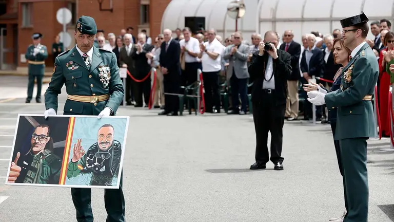 El coronel José Miguel Barbero (d), Jefe de la Guardia Civil en Navarra y la delegada del Gobierno en la comunidad foral, Alicia Echeverria, aplauden al capitán de la 2ª Compañía del GAR destacada en San Sebastián Álvaro Ruiz (i) tras entregarle un dibujo con los rostros de los Guardias Civiles asesinados el pasado 9 de febrero en Barbate obsequio de la Comandancia de Teruel, durante los actos que se han organizado este lunes con motivo de la celebración del 180 aniversario de la fundación de la Guardia Civil en Navarra. EFE/ Jesús Diges