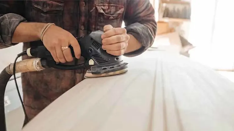 Un carpintero lijando un tablón de madera. UNSPLASH