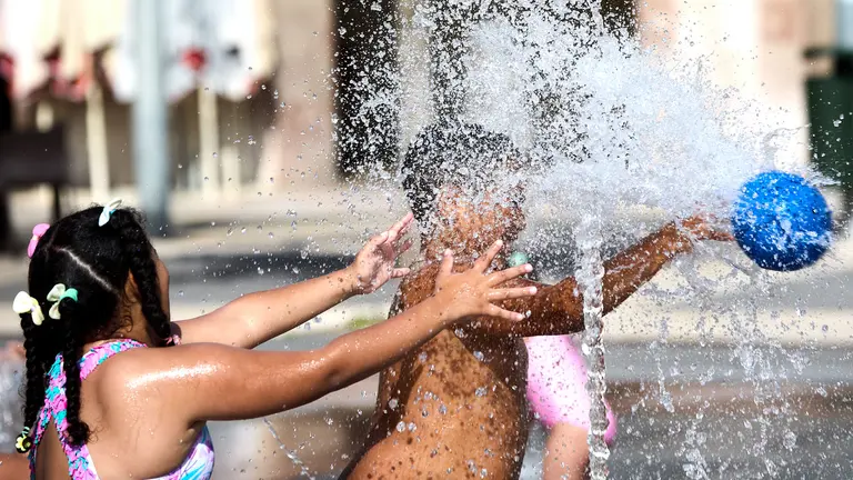 Unos niños juegan en la Fuente de los Chorros en el parque de Yamaguchi de Pamplona en el primer día de una nueva ola de calor de este verano. IÑIGO ALZUGARAY