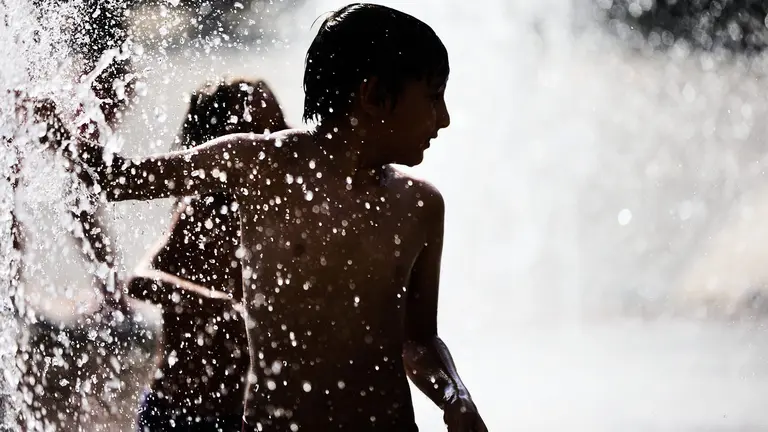 Unos niños juegan en la Fuente de los Chorros en el parque de Yamaguchi de Pamplona en el primer día de una nueva ola de calor de este verano. IÑIGO ALZUGARAY