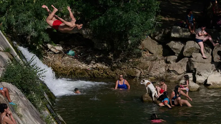 Varias personas se refrescan en la presa de la localidad navarra de Huarte en una jornada en la que la comunidad Foral se encuentra en alerta naranja por la primera ola de calor que afecta a más de media Españ . EFE/Iñaki Porto