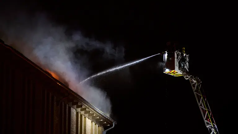 Los bomberos trabajan por la noche en la extinción de incendio originado en las dependencias de la Policía Municipal de Pamplona. PABLO LASAOSA