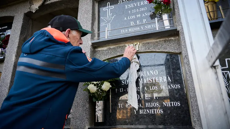 Varias personas llevan flores a sus sere queridos durante la celebración de Todos los Santos en el cementerio de Pamplona. PABLO LASAOSA
