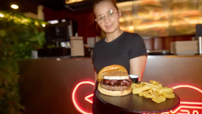 Michelle Sarango con una hamburguesa de Bronx Burger, en la calle del monasterio de Urdax 49 de Pamplona. IÑIGO ALZUGARAY