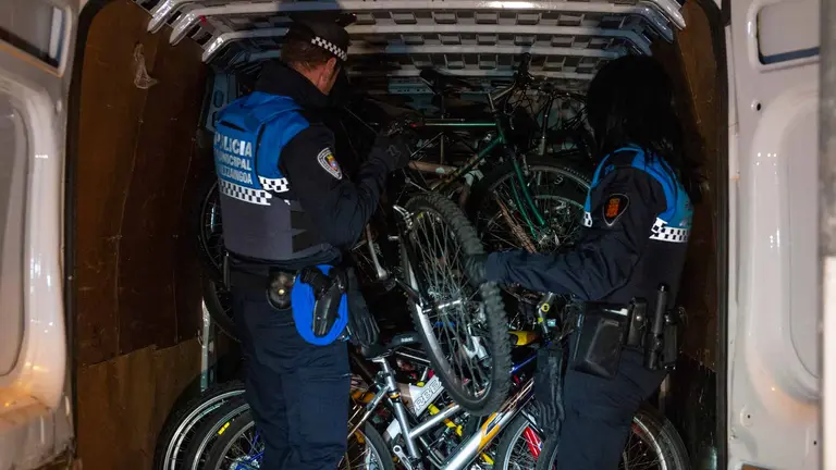 Dos agentes de la Policía Municipal de Pamplona ayudan a cargar una furgoneta con las 44 bicis que viajarán a Valencia. AYUNTAMIENTO DE PAMPLONA