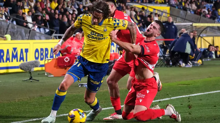 El delantero de Las Palmas Fabio Silva (i) intenta escaparse de Iker Muñoz (d), de Osasuna, durante el partido de LaLiga entre la UD Las Palmas y el Osasuna, este viernes en el estadio de Gran Canaria. EFE/ Angel Medina G.