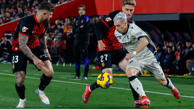El centrocampista del Mallorca Robert Navarro (c) pelea un balón con el delantero de Osasuna Bryan Zaragoza (d) en el partido de LaLiga entre el Mallorca y el Osasuna, este lunes en el estadio de Son Moix, en Palma. EFE/CATI CLADERA