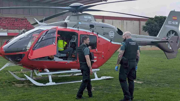 Efectivos de la Guardia Civil junto al helicóptero de emergencias sobre el campo de fútbol de Castejón. GUARDIA CIVIL