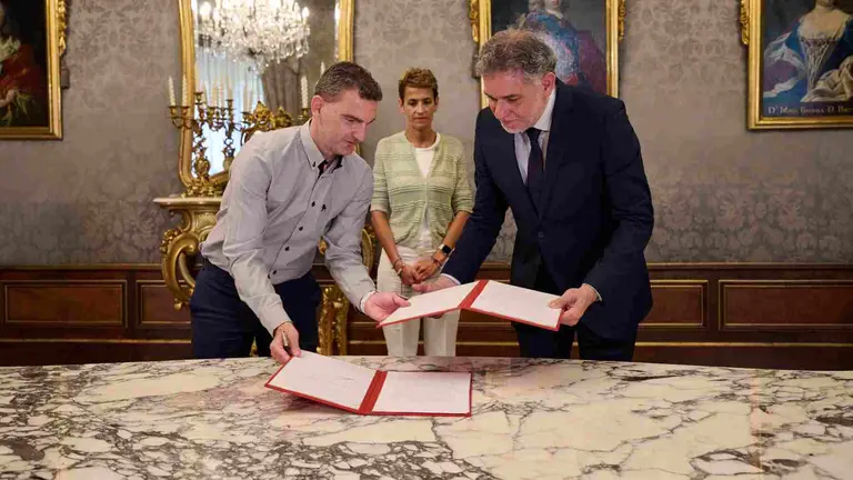 El director general de Digitalización y Recursos Educativos, Luis Calatayud, y el catedrático de Periodismo de la Universidad de Navarra, Ramón Salaverría intercambian el convenio en presencia de la Presidenta Chivite. GOBIERNO DE  NAVARRA
