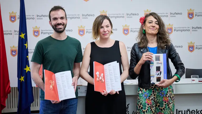 La concejala delegada de Cultura, Fiestas, Educación y Deporte, Maider Beloki, el director del área, Ínigo Gómez, y la autora del concepto, diseño e ilustraciones del programa, Liébana Goñi presentan el programa oficial de las fiestas de San Fermín 2025. PABLO LASAOSA