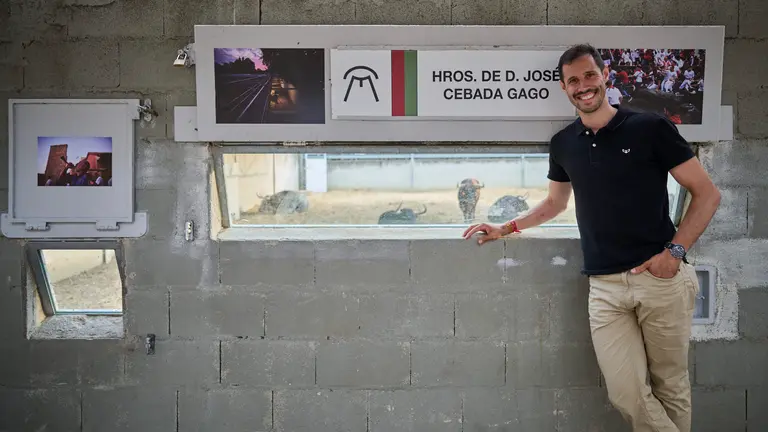 El fotógrafo Pablo Lasaosa posa junto a sus fotos en los Corrales del Gas, al fondo, toros de Cebada Gago. PABLO SÁNCHEZ