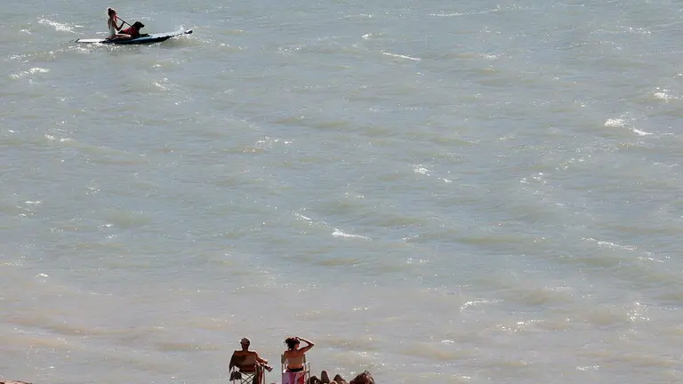 Una persona junto a su perro navegan sobre una tabla en el pantano de Yesa mientras algunos toman el sol en la orilla del embalse. La últimas lluvias caídas en la Comunidad Foral no han logrado paliar la falta de agua en los pantanos. El volumen de agua embalsada en la cuenca hidrográfica del Ebro se sitúa en el 51,6 % de su capacidad, con 4.086 hectómetros cúbicos de los 7.917 que pueden albergar en su totalidad, tras perder un 0,4 % de su capacidad en la última semana. Según los datos proporcionados por la Confederación Hidrográfica del Ebro (CHE), en la misma semana del año pasado la situación era de 4.714 hm³, correspondiente al 59,5 % de la capacidad total. EFE/ Jesús Diges