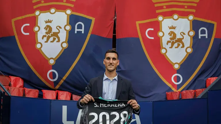 El portero de Oasuna Sergio Herrera posa para los gráficos con la camiseta de la renovación tras la rueda de prensa que ha ofrecido este martes en el estadio de El Sadar para anunciar su acuerdo con el club navarro hasta 2028 y en la que el guardameta ha afirmado que deberá “volver a rendir al máximo nivel”. EFE/ Villar López