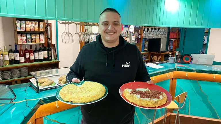 Jonnathan sostiene dos bandejas con tortillas de patata en el bar Olazti de Pamplona. Navarra.com
