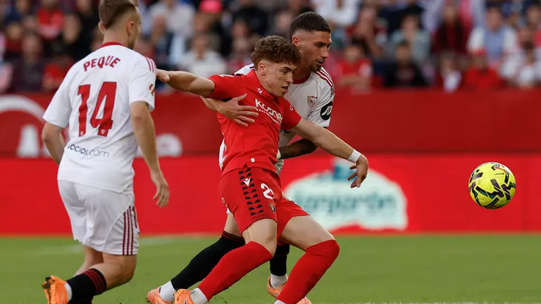 El defensa del Sevilla José Ángel Carmona (d) disputa un balón con el delantero del Osasuna Víctor Muñoz (c) durante el encuentro correspondiente a la jornada 12 de LaLiga entre Sevilla FC y CA Osasuna celebrado este sábado en el estadio Ramón Sánchez-Pizjuán de Sevilla. EFE/ Julio Muñoz
