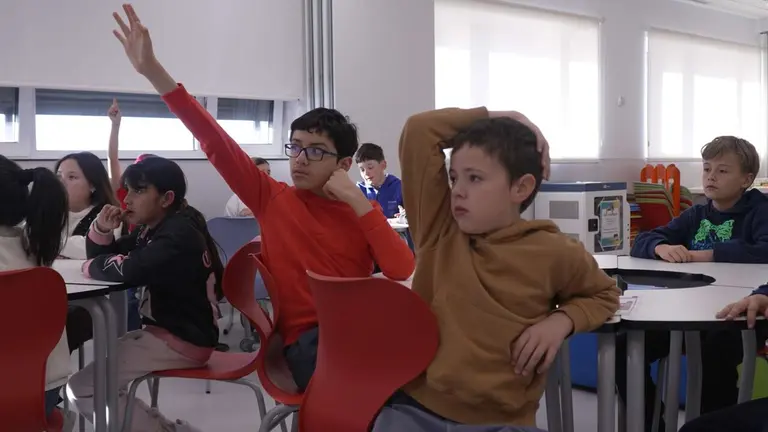 Escolares levantan la mano en el aula de un colegio. AYUNTAMIENTO DE PAMPLONA
