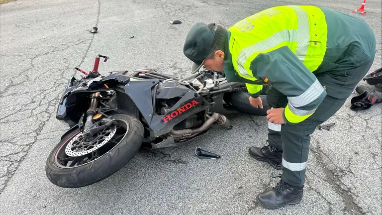 Un guardia civil revisa el estado en el que ha quedado la moto del accidentado. GUARDIA CIVIL