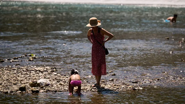 Decenas de personas aprovechan las altas temperaturas para refrescarse y disfrutar del r&iacute;o Arga a su paso por Pamplona. PABLO LASAOSA