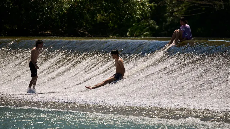 Decenas de personas aprovechan las altas temperaturas para refrescarse y disfrutar del r&iacute;o Arga a su paso por Pamplona. PABLO LASAOSA