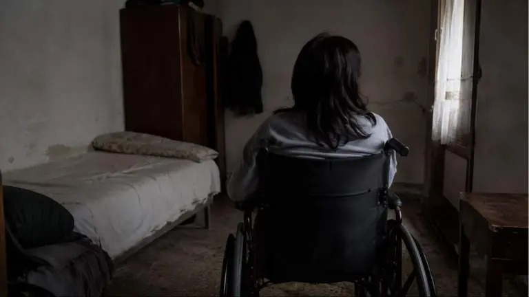 Una mujer en silla de ruedas en una habitaci&oacute;n.