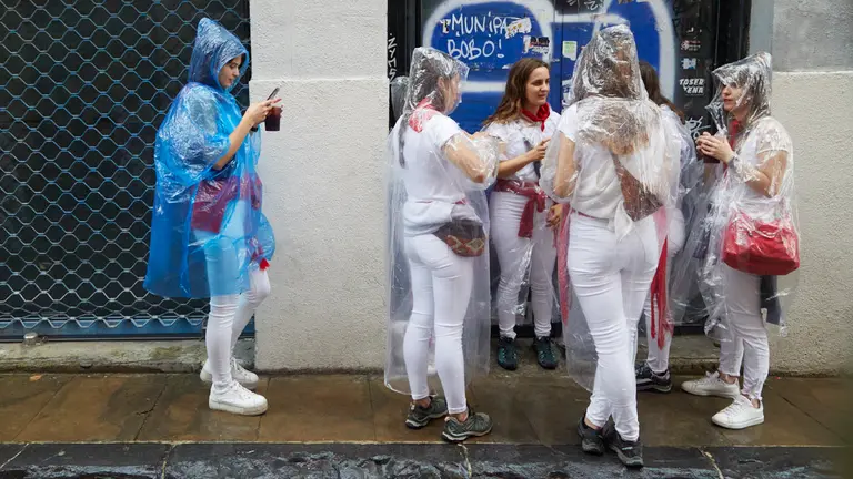 Ambiente por las calles de Pamplona en los momentos posteriores al Chupinazo con el que se ha dado inicio a los Sanfermines 2022, este año con la lluvia como portagonista. IÑIGO ALZUGARAY