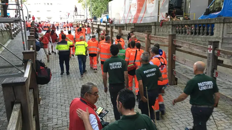 Voluntarios de la Cruz Roja y pastores se dirigen a ocupar sus posiciones antes comienzo del último encierro de San Fermín 2023 con toros de la ganadería Miura. IÑIGO ALZUGARAY