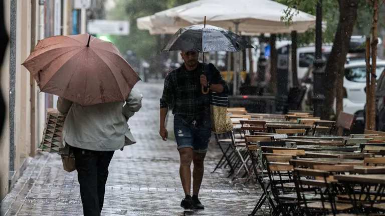 Dos personas se resguardan bajo un paraguas de la lluvia. DIEGO RADAMÉS / EUROPA PRESS
