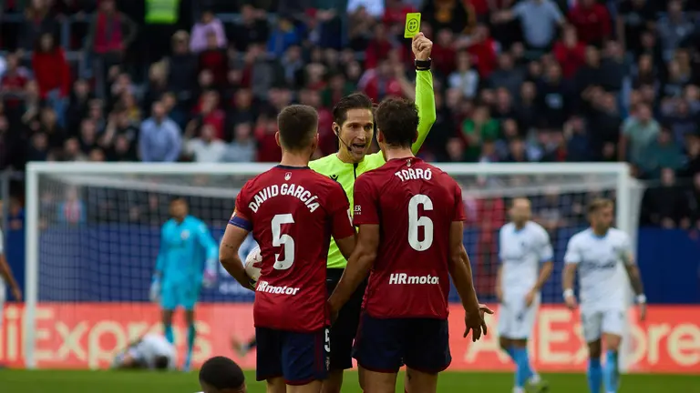 José Luis Munuera muestra una tarjeta amarilla a Lucas Torró (6. CA Osasuna) durante el partido de La Liga EA Sports entre CA Osasuna y Girona FC disputado en el estadio de El Sadar en Pamplona. IÑIGO ALZUGARAY