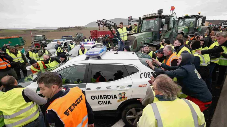 Agricultores en los accesos a Pamplona por el nudo de Cizur donde han apartado un coche patrulla de la Guardia Civil para poder pasar. EFE