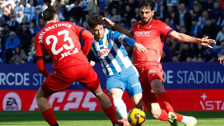 Pol Lozano (c), del Espanyol, se enfrenta a Abel Bretones (i), del Osasuna, durante su partido de la jornada 17 LaLiga de fútbol, este sábado en el RCDE Stadium, en Cornellà de Llobregat (Barcelona). EFE/ Andreu Dalmau