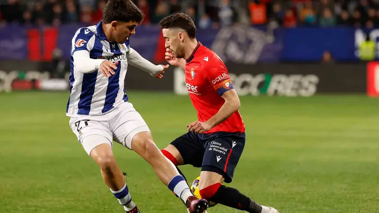 El centrocampista de Osasuna, Kike Barja (d), disputa el balón ante el defensa de la Real Sociedad, Jon Aramburu, durante el encuentro correspondiente a la jornada 22 de Laliga EA Sports que disputan hoy domingo Osasuna y Real Sociedad en el estadio El Sadar de Pamplona. EFE / Villar López.