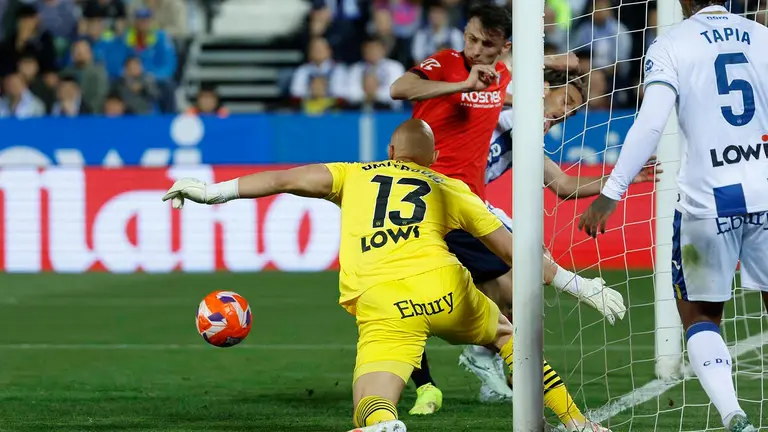 El centrocampista de Osasuna Aimar Oroz (arriba) trata de superar al portero Marko Dmitrovic, del Leganés, durante el partido de LaLiga en Primera División que CD Leganés y CA Osasuna disputan este lunes en el Estadio Municipal de Butarque. EFE/Juanjo Martín