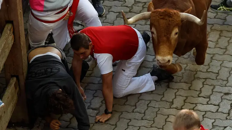 Varios corredores caen al paso de uno de los toros de la ganadería Álvaro Núñez durante el tercer encierro de los Sanfermines 2025 este miércoles en Pamplona. EFE/ Villar López