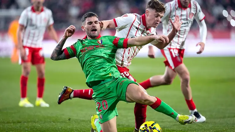 El defensa de Osasuna, Javi Galán (i), cae ante el delantero ucraniano del Girona, Vladyslav Vanat, durante el encuentro correspondiente a la jornada 19 de Laliga EA Sports que disputan hoy sábado Girona y Osasuna en el estadio municipal de Montilivi, en la capital gerundense. EFE/David Borrat.