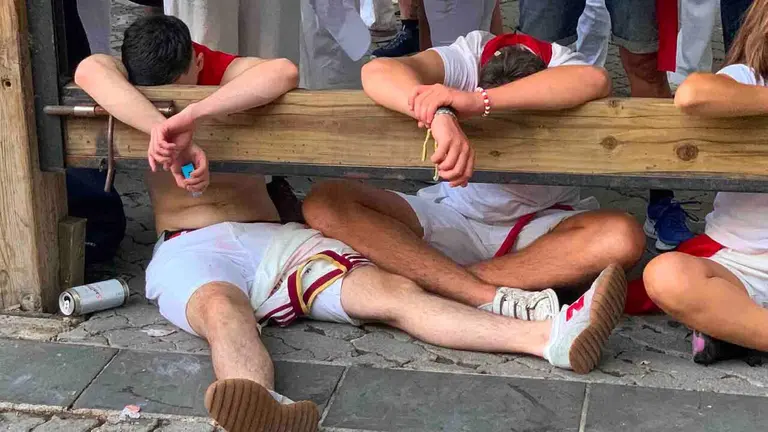Varias personas, derrotadas en el vallado tras toda una noche de fiesta.