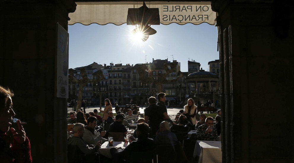 Varias personas disfrutan del buen tiempo en Pamplona.