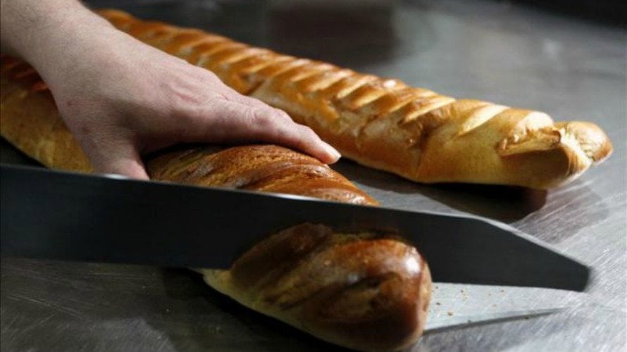 Un repostero corta una barra de pan en una pastelería de España. EFE.