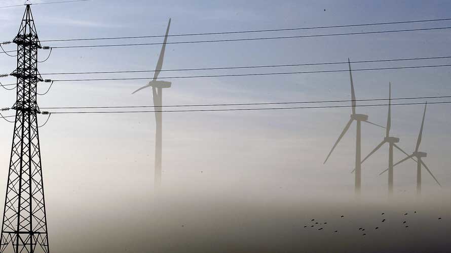 Molinos de viento y torres electricas difuminados por la niebla.