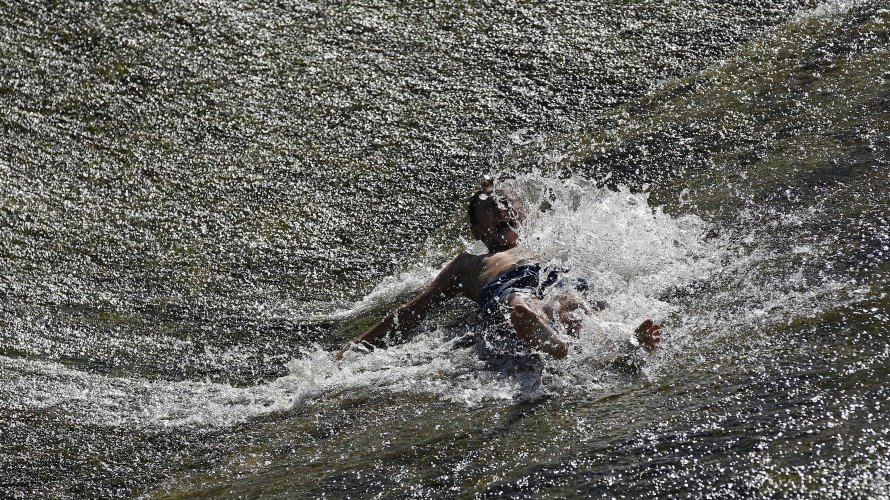 Tiempo. Un joven se divierte en el río Arga a su paso por Pamplona.  EFEVillar López