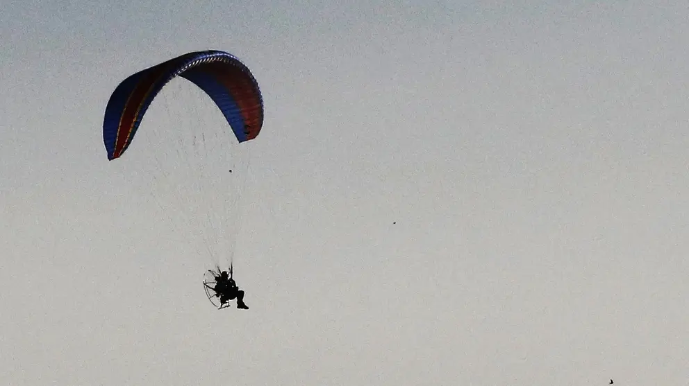 Un parapente con motor sobrevuela por un parque e&oacute;lico en la localidad de Falces, en una jornada en la que el buen tiempo,  las altas temperaturas y la ausencia de viento permiten disfrutar desde el aire de unas privilegiadas panor&aacute;micas. EFE/Jes&uacute;s Diges