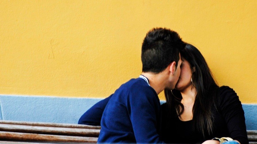 Una pareja se besa en un banco. FLICKR