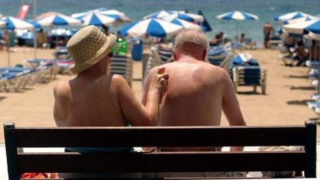 Dos ancianos se esparcen crema en la playa. EFE